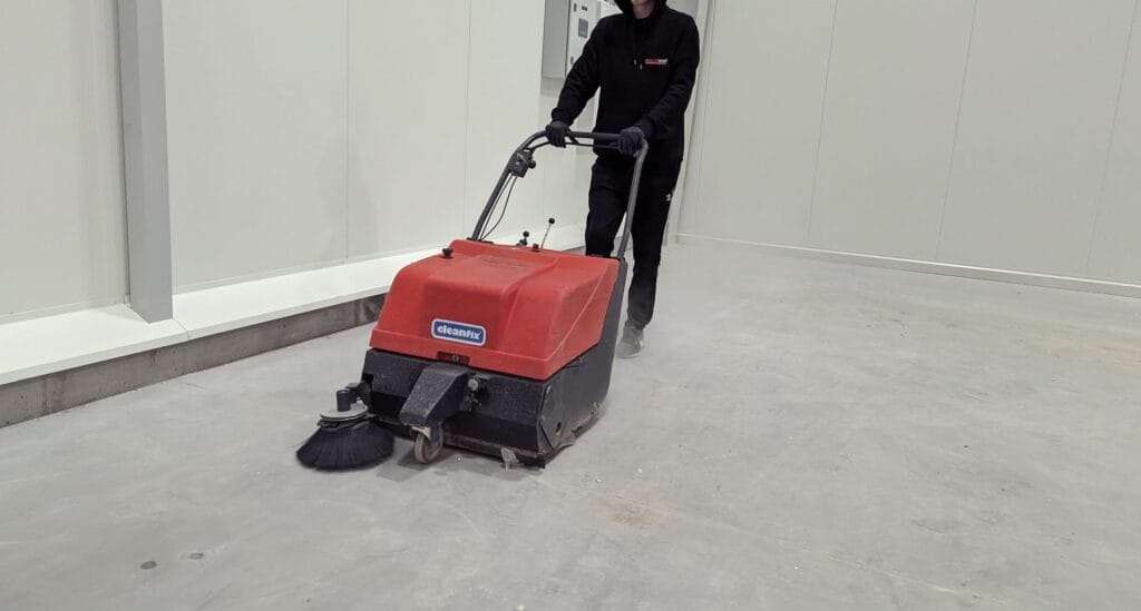 Pracownik Solid Work, myjący maszyną posadzkę w trakcie sprzątania specjalistycznego dla firmy Halbud