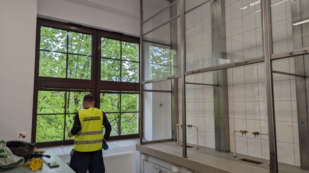 Pracownik Solid Work czyszczący szklaną ścianę po remoncie Instytutu Chemii dla Grupy KDM
