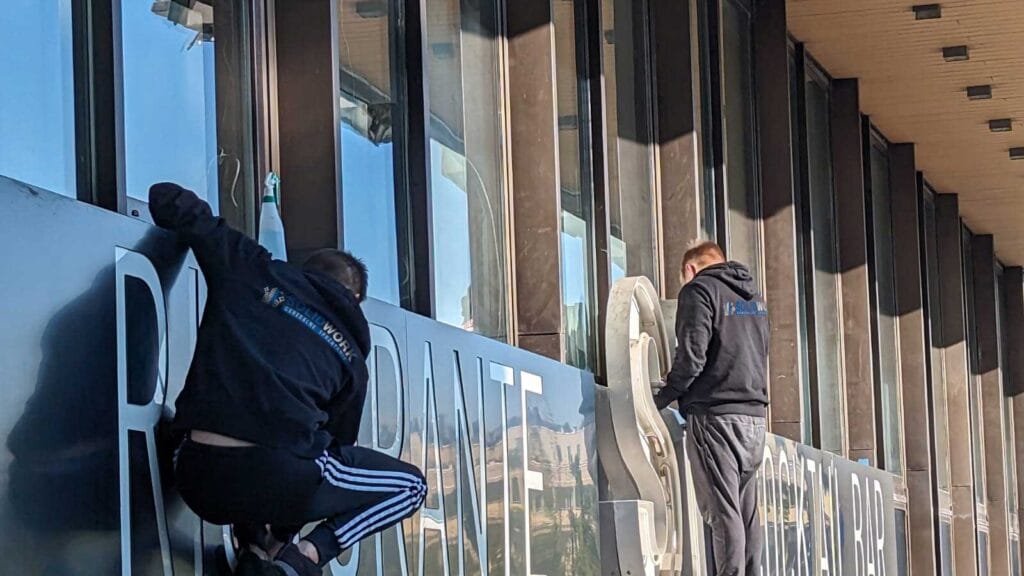 Pracownicy Solid Work czyszczący specjalistycznie szyld Restauracji SI