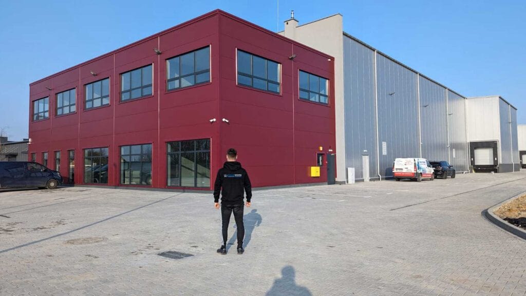 Pracownik Solid Work z logo na plecach swojej bluzy przed magazynem firmy Halbud