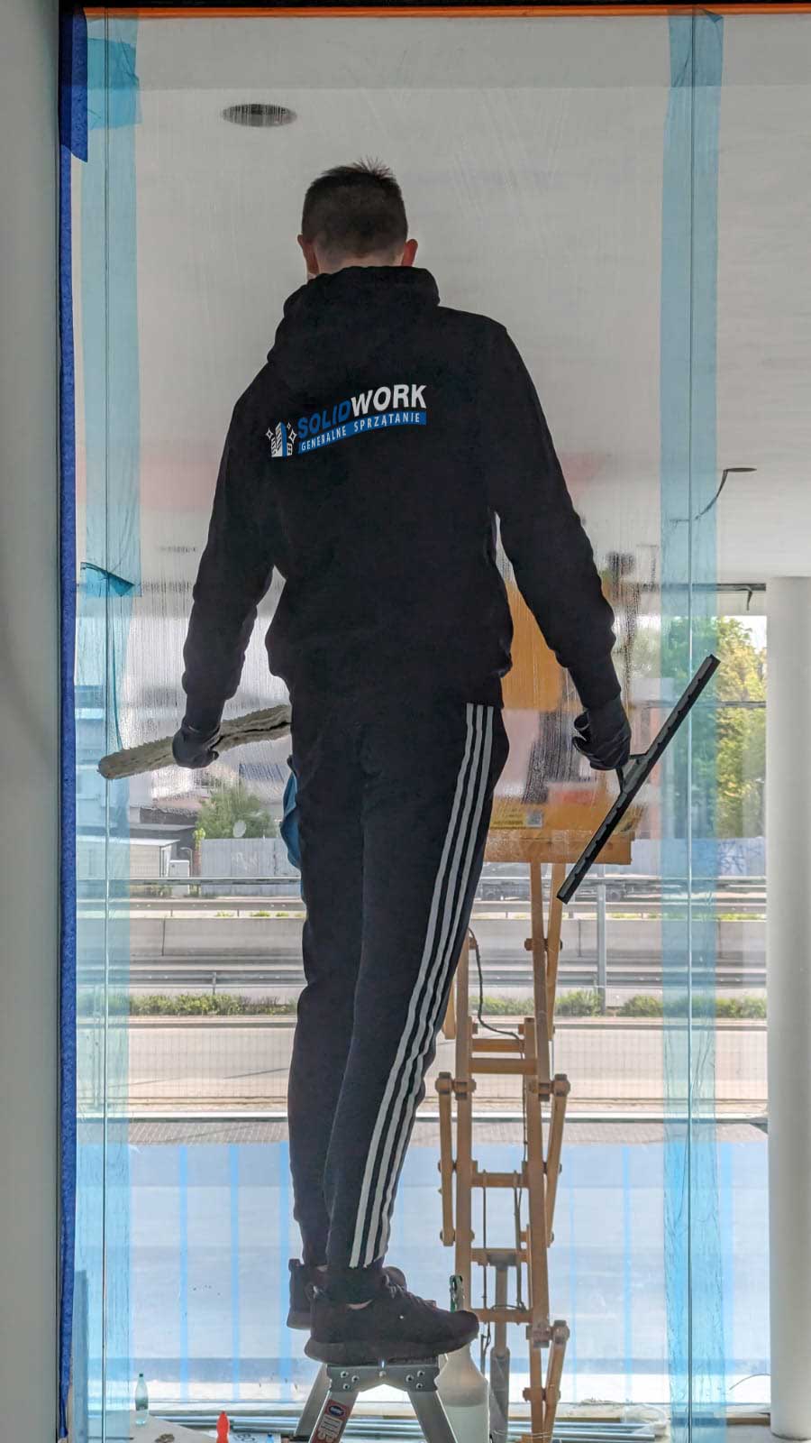 Pracownik Solid Work czyszczący okna w firmie Mercedes Benz